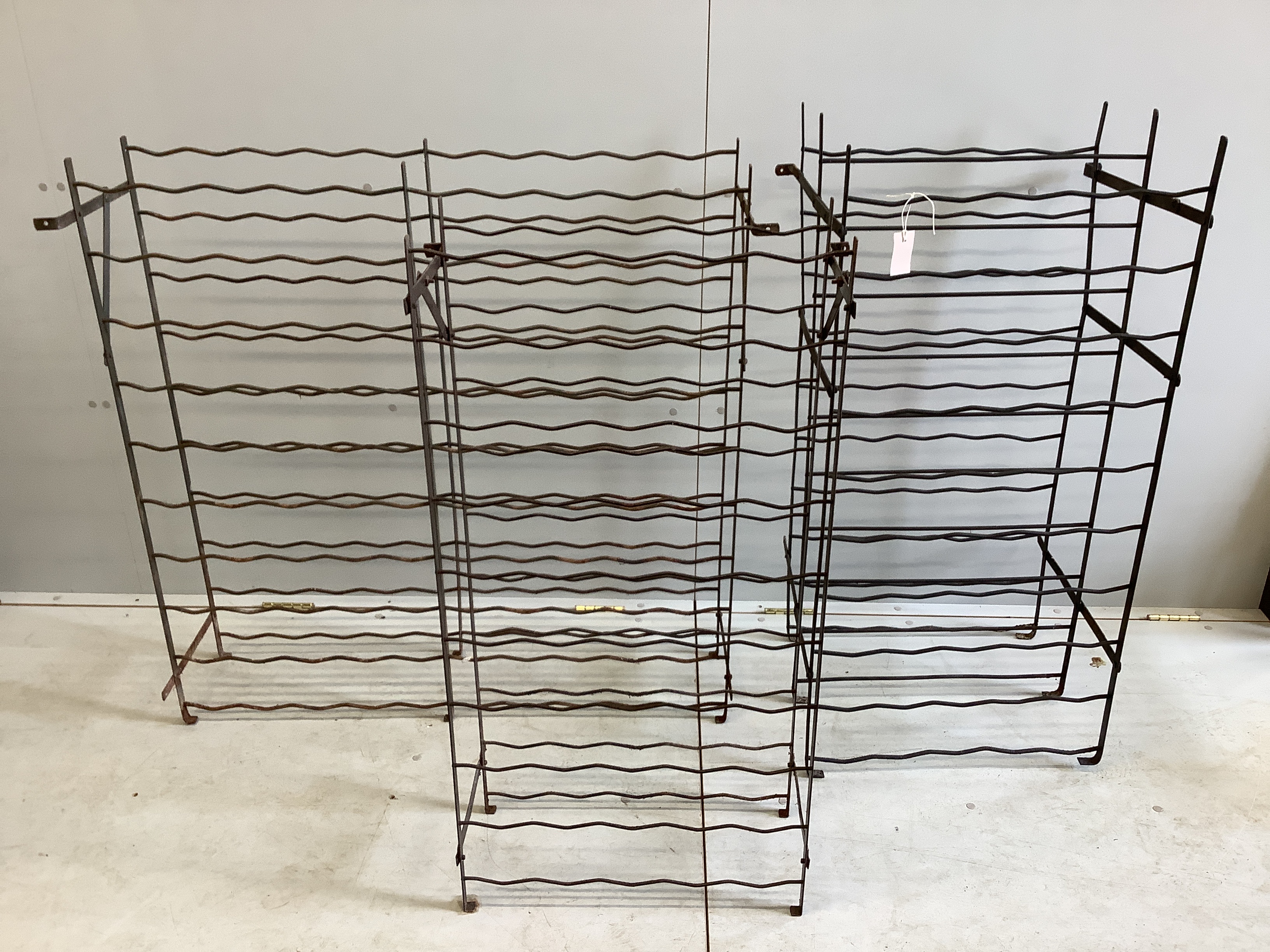Three vintage wrought iron wine racks, largest height 106cm